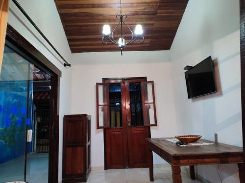a room with a table and a tv and a chandelier at Pousada L'étage in Búzios