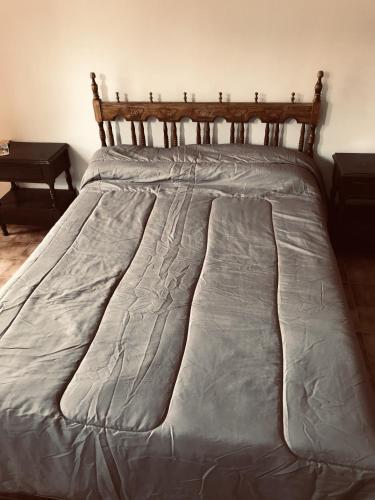 Una cama con un edredón gris. en Complejo Altas Cumbres en Villa Cura Brochero