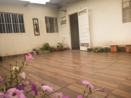 an empty room with a wooden floor and flowers at Quarto em Caraguatatuba litoral norte in Caraguatatuba