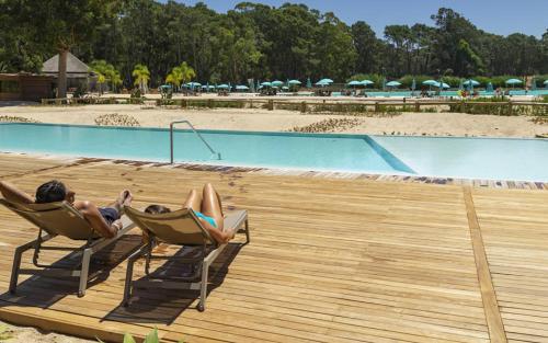 two people laying in lawn chairs next to a pool at Solanas Forest Semana in Punta del Este