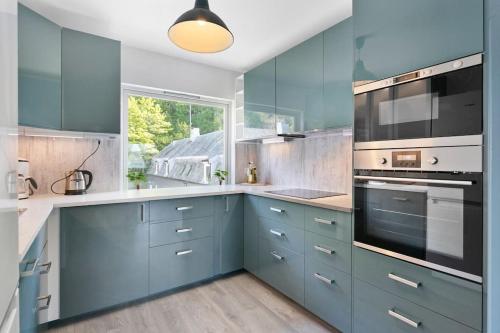 a kitchen with blue cabinets and a large window at koselig sentrum leilighet. in Ålesund