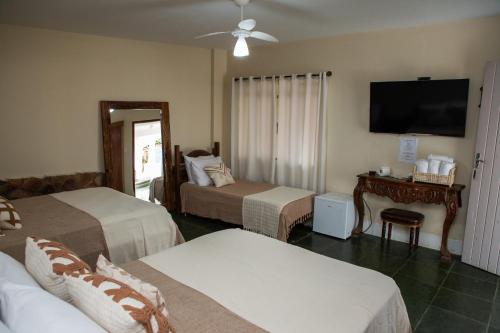a hotel room with two beds and a flat screen tv at Pousada do Beco in Tiradentes
