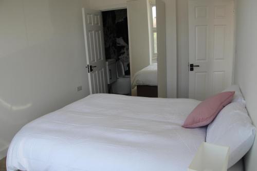 Double Bedroom with Marble private bathroom في إدجوير: سرير أبيض مع وسائد وردية في غرفة النوم