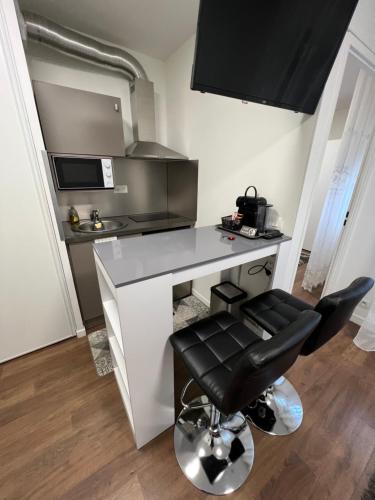 a kitchen with a counter and a black chair at 2 PIECES proche du centre PARIS 15 min in Rosny-sous-Bois