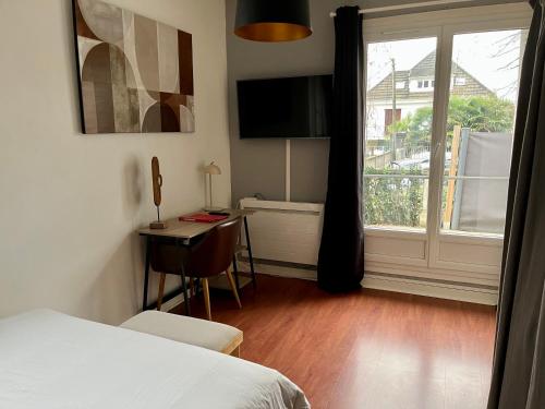 a bedroom with a bed and a window and a desk at Appartement Proche de Disneyland & Paris in Noisy-le-Grand