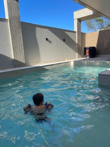 a young boy swimming in a swimming pool at Apto inteiro 2 quartos, condomínio com piscina aquecida in Bombinhas