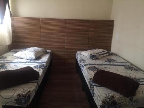 two twin beds in a room with wooden walls at Pousada Familia Aparecida in Aparecida