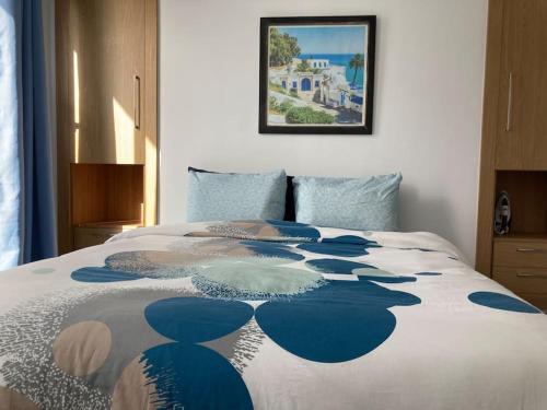 uma cama com um cobertor azul e branco em Diamant de la marsa plage em La Marsa