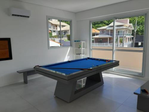 uma mesa de bilhar num quarto com janelas em Casa c/ SPA e mesa de sinuca 240 m2 em Florianópolis