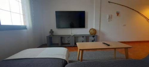 sala de estar con sofá, mesa y TV en Casa Faro de Arinaga en Arinaga