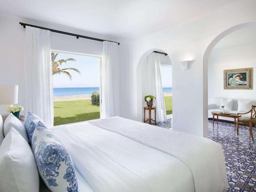 a bedroom with a large bed with a view of the ocean at Caramel Grecotel Boutique Resort in Adelianos Kampos