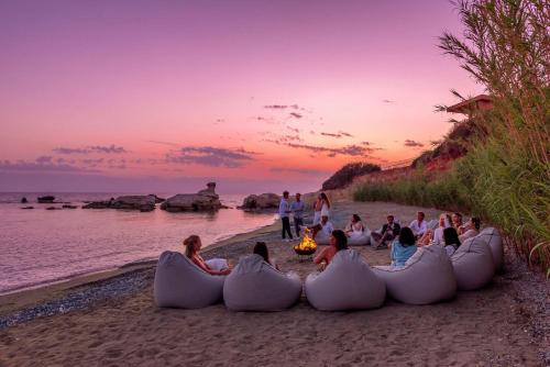 a group of people sitting around a fire on a beach at Cap St Georges Hotel & Resort in Peyia