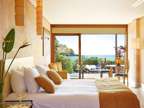 a bedroom with a bed with a view of the ocean at Cape Sounio Grecotel Boutique Resort in Sounio