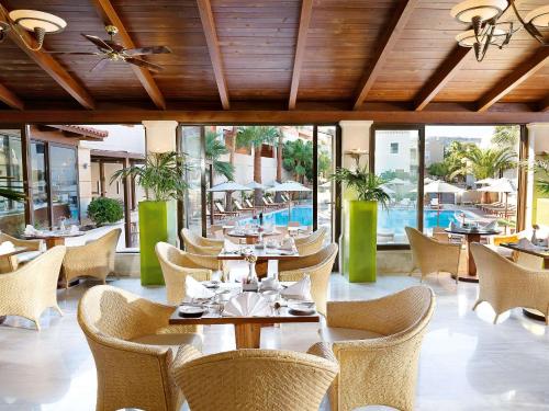 een restaurant met tafels en stoelen en een zwembad bij Grand Leoniki Residence by Grecotel in Platanes