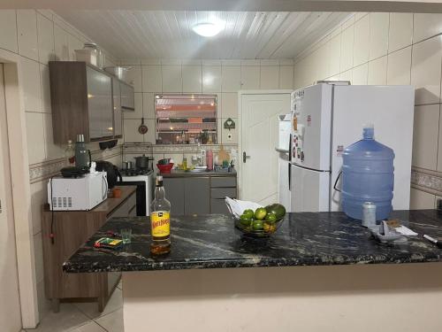 a kitchen with a counter with a bottle and a bowl of fruit at Lohighfive in Florianópolis