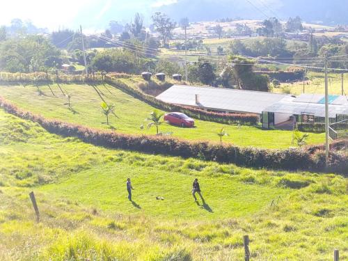 dos personas caminando en un campo de hierba con un edificio en Hotel Chimeneas del Dorado, en Sesquilé