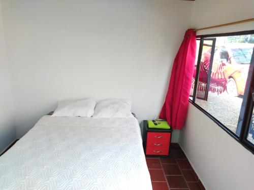 a small bedroom with a bed and a window at Hotel Chimeneas del Dorado in Sesquilé