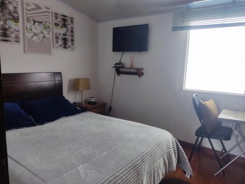 sypialnia z łóżkiem, biurkiem i oknem w obiekcie Excelente cómoda habitación privada cerca parque Simon Bolivar w mieście Bogota