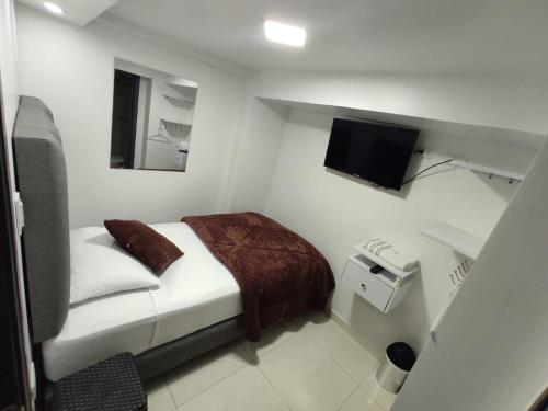 a small white room with a bed and a television at Hotel Casa Blanca in Aguadas