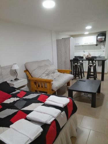 1 dormitorio con cama, mesa y cocina en monoambiente Albarracín en San Carlos de Bariloche