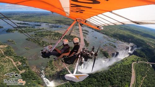 a group of people riding on a glider over a waterfall at Muke Village Guest House in Livingstone