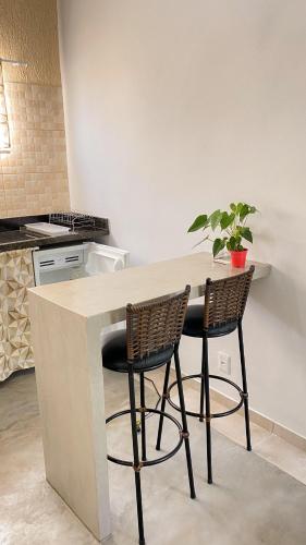 a kitchen with a counter with two chairs and a table at Espaço Zoey in Búzios