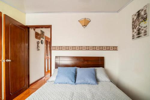 Un dormitorio con una cama con almohadas azules. en Excelente cómoda habitación privada cerca parque Simon Bolivar, en Bogotá
