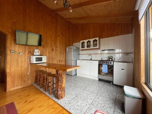 - une cuisine avec des murs en bois, une table en bois et des appareils électroménagers dans l'établissement Hermosa cabaña a pasos de la playa, à Castro
