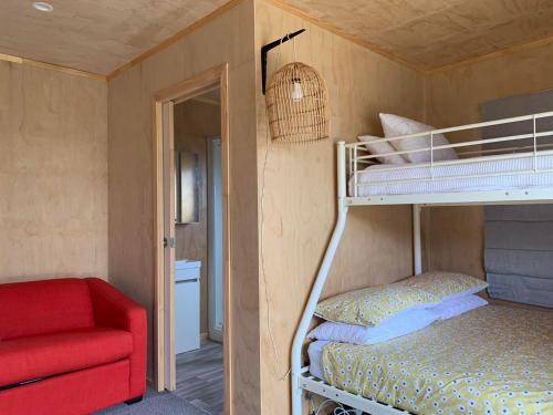 a bedroom with a bunk bed and a red chair at Charming on Charles in Cooks Beach