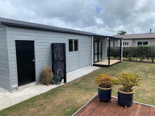 a gray building with two potted plants in a yard at Charming on Charles in Cooks Beach