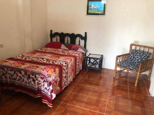 een slaapkamer met een bed en een stoel bij hospedaje Maluli suit 2 in Santa Elena