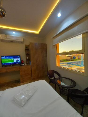 a bedroom with a bed and a tv and a window at دايموند Diamond in Al-ʿUla