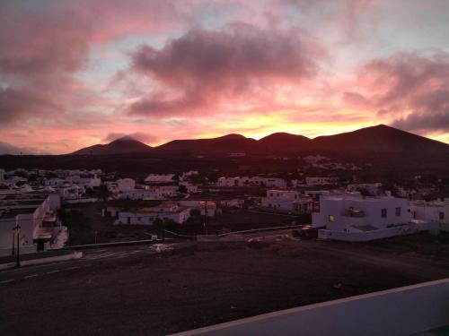 una puesta de sol sobre una ciudad con montañas en el fondo en Tranquilidad entre volcanes, en Uga