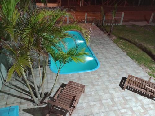 ein blauer Pool mit einer Bank und einer Palme in der Unterkunft Casa Praia Ribeiro SC in Passo de Torres