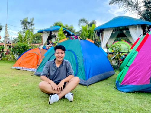 un uomo seduto di fronte a un gruppo di tende di CABANACAN MODERN CAMPSITE 