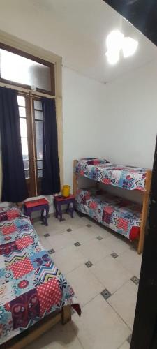 a room with three beds and a window and a floor at Hospedaje La Rana in Buenos Aires