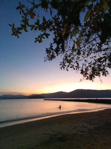 a person walking on the beach at sunset at Suítes Canto do Pontal in Paraty