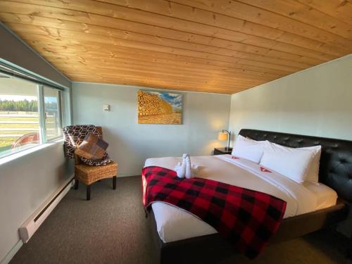 a bedroom with a large bed and a chair at Woodhouse Cottages And Ranch in Prince George
