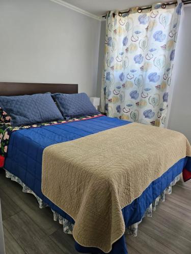 a bedroom with a bed with a blue comforter at Condominio Florencia 524 in La Serena