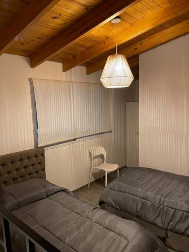 a bedroom with two beds and a chair and a light at Depto funcional en Comodoro! in Comodoro Rivadavia