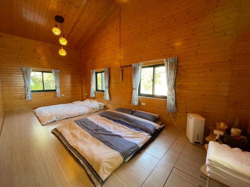 two beds in a room with wooden walls and windows at 雲熙莊園 in Renai