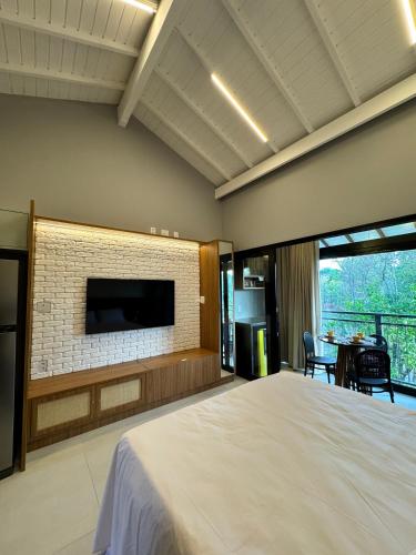a bedroom with a large bed and a brick fireplace at Apartamento studio novo e completo em Praia do Forte! 900m da Vila! in Praia do Forte