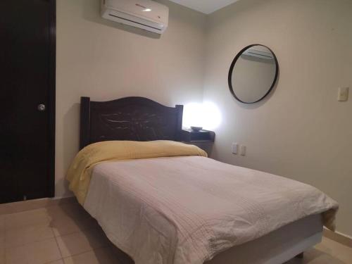 Dormitorio con cama con espejo y lámpara en Depa independiente con Terraza Super ubicado ., en Ciudad Madero