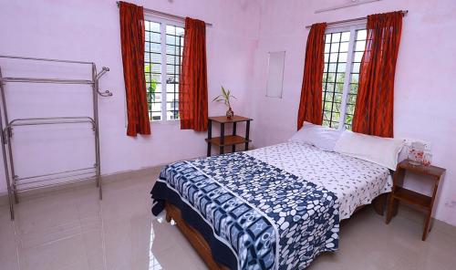 1 dormitorio con 1 cama y 2 ventanas en Blooms home stay, en Thekkady