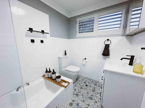 a white bathroom with a toilet and a sink at Harbourside Bliss: 2-Bedroom Coastal Apartment in Wollongong