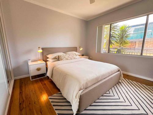 a bedroom with a large bed and a window at Harbourside Bliss: 2-Bedroom Coastal Apartment in Wollongong