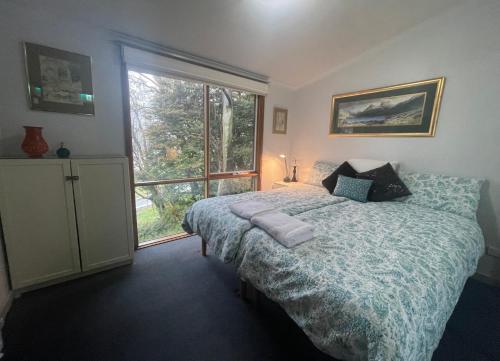 a bedroom with a bed and a large window at Halls Retreat - Luxury with a spa in Baw Baw Village