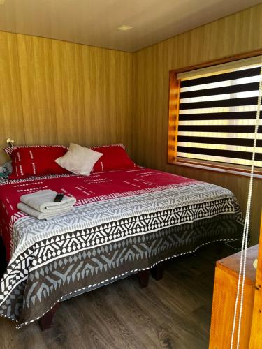 um quarto com uma cama com lençóis vermelhos e uma janela em Alojamiento Rustico Belloto (2) em Quilpué