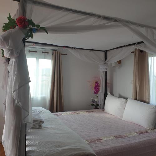 1 dormitorio con cama con dosel y rosas. en สวนมรดกดอย 
