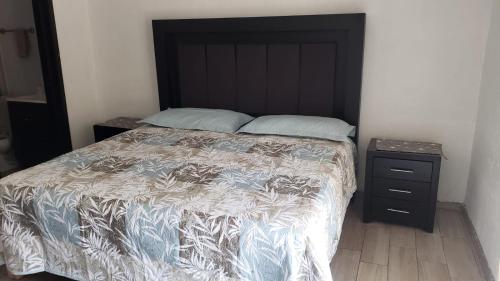 een slaapkamer met een bed met een zwart hoofdeinde en een nachtkastje bij Cabaña de lujo con Terraza para eventos in San José del Puente
